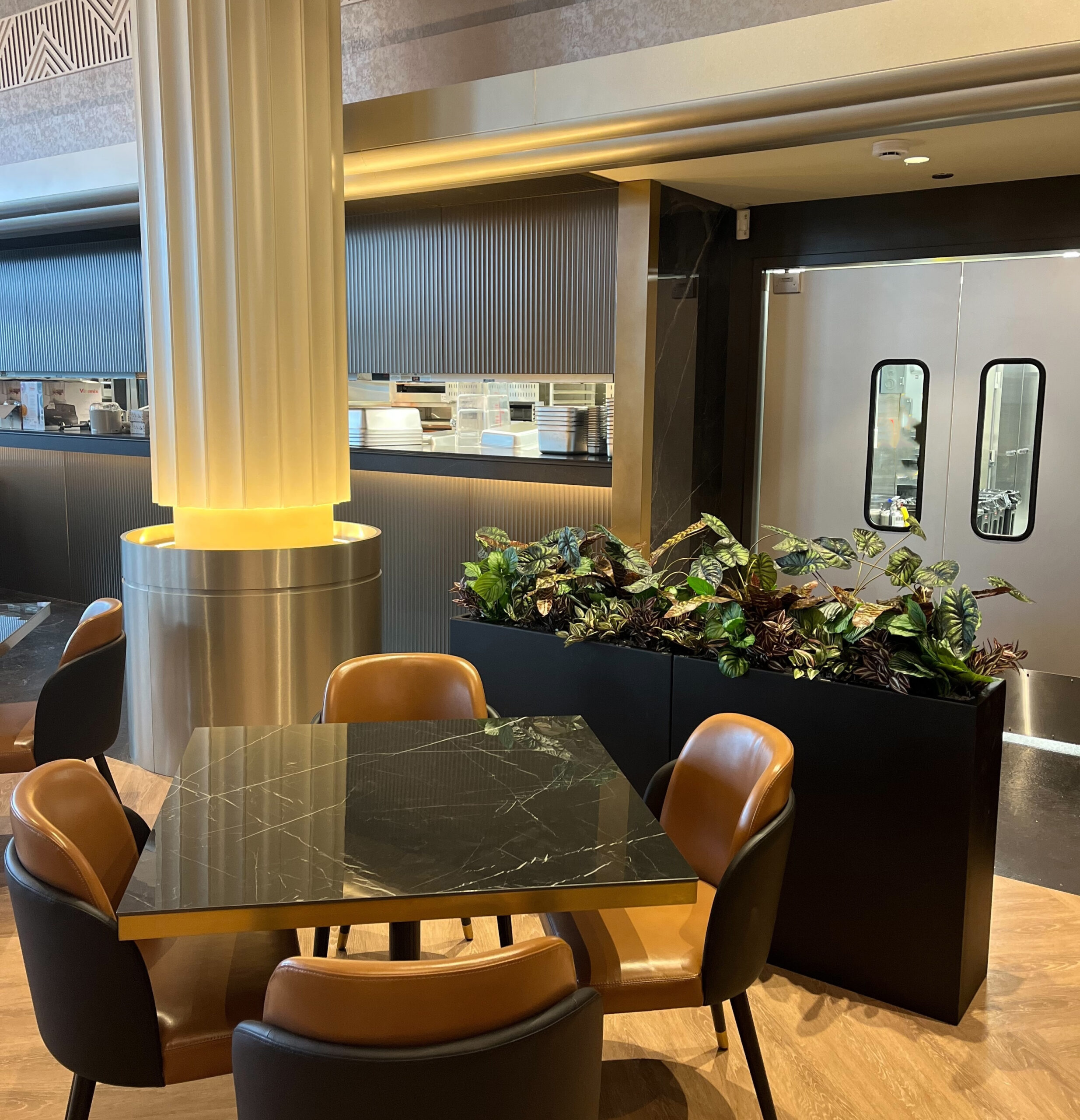 Artificial potted plants used as a divider planter between dining and service areas