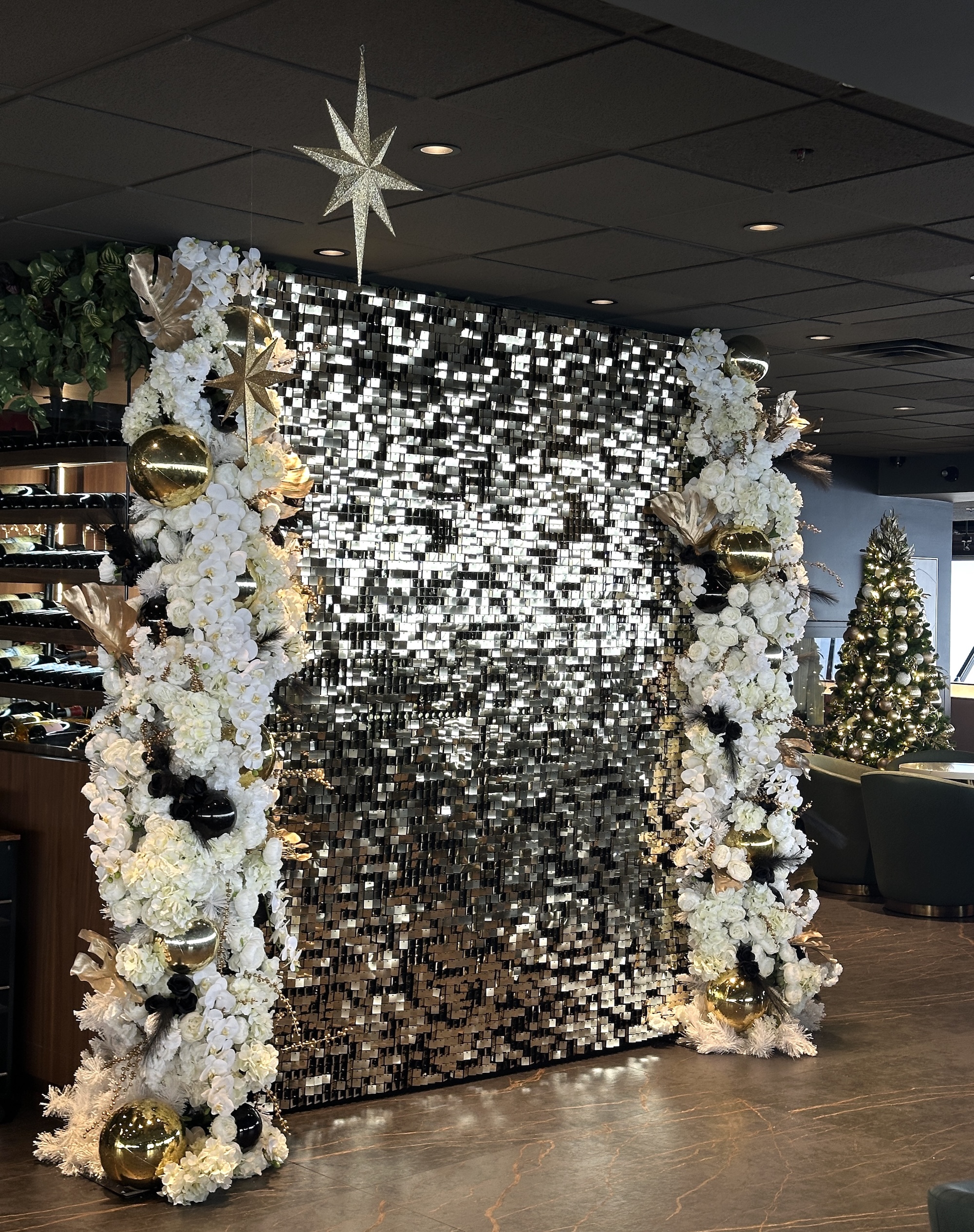 Sequin backdrop with white florals and décor for New Year’s Eve event