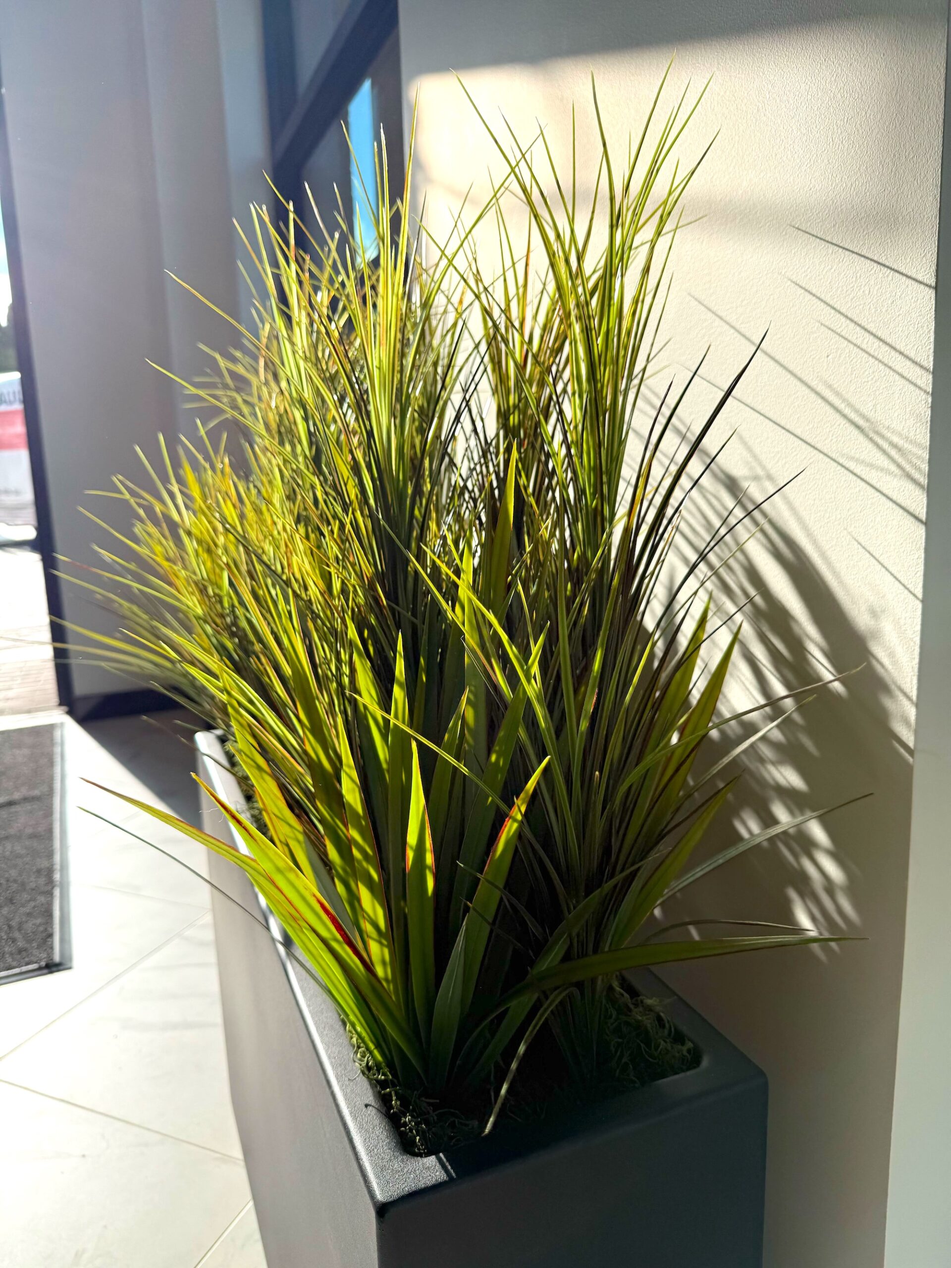 Close-up of replica potted grass arranged in a modern indoor planter