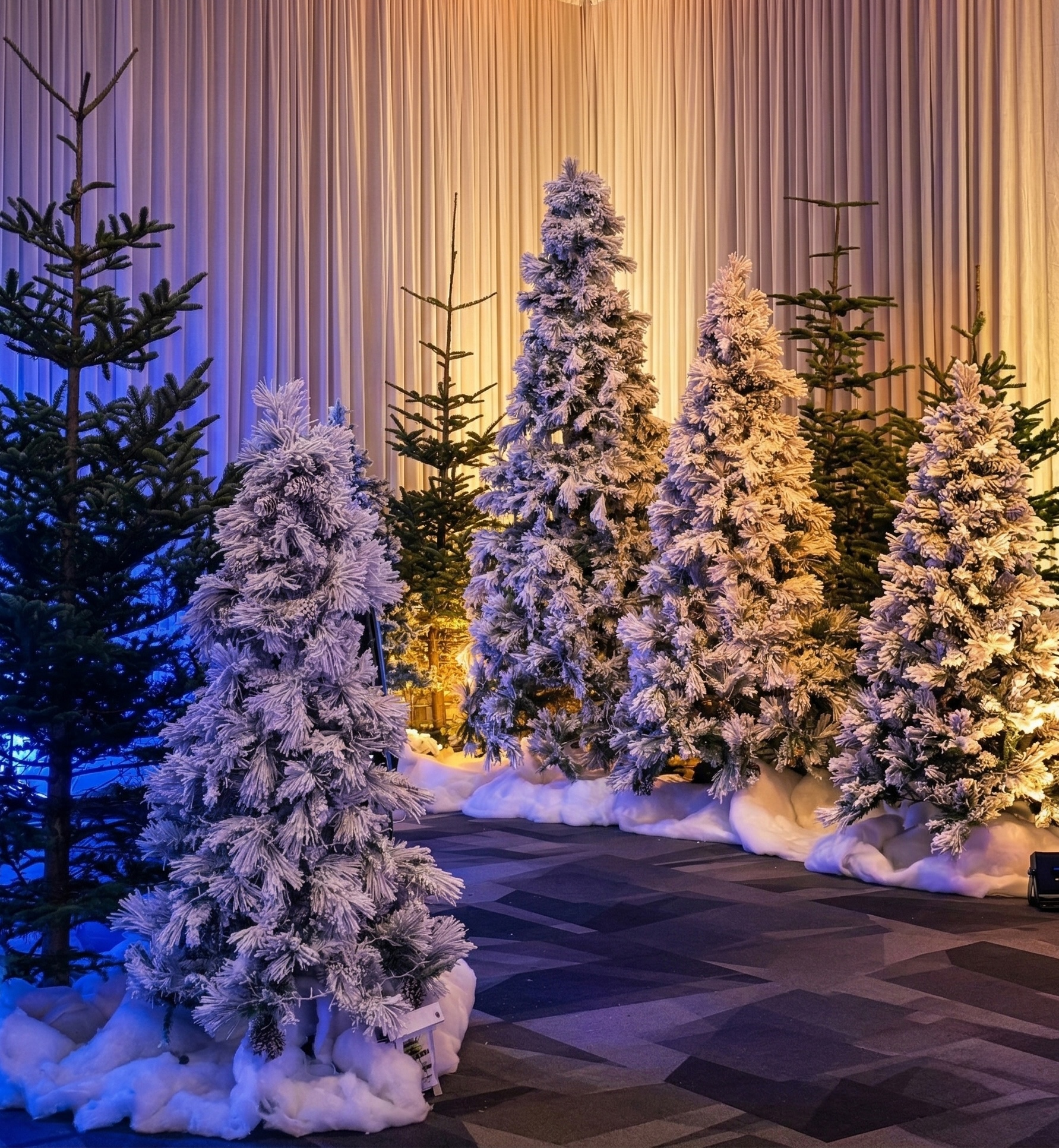 Snow covered Christmas trees arranged in indoor holiday display