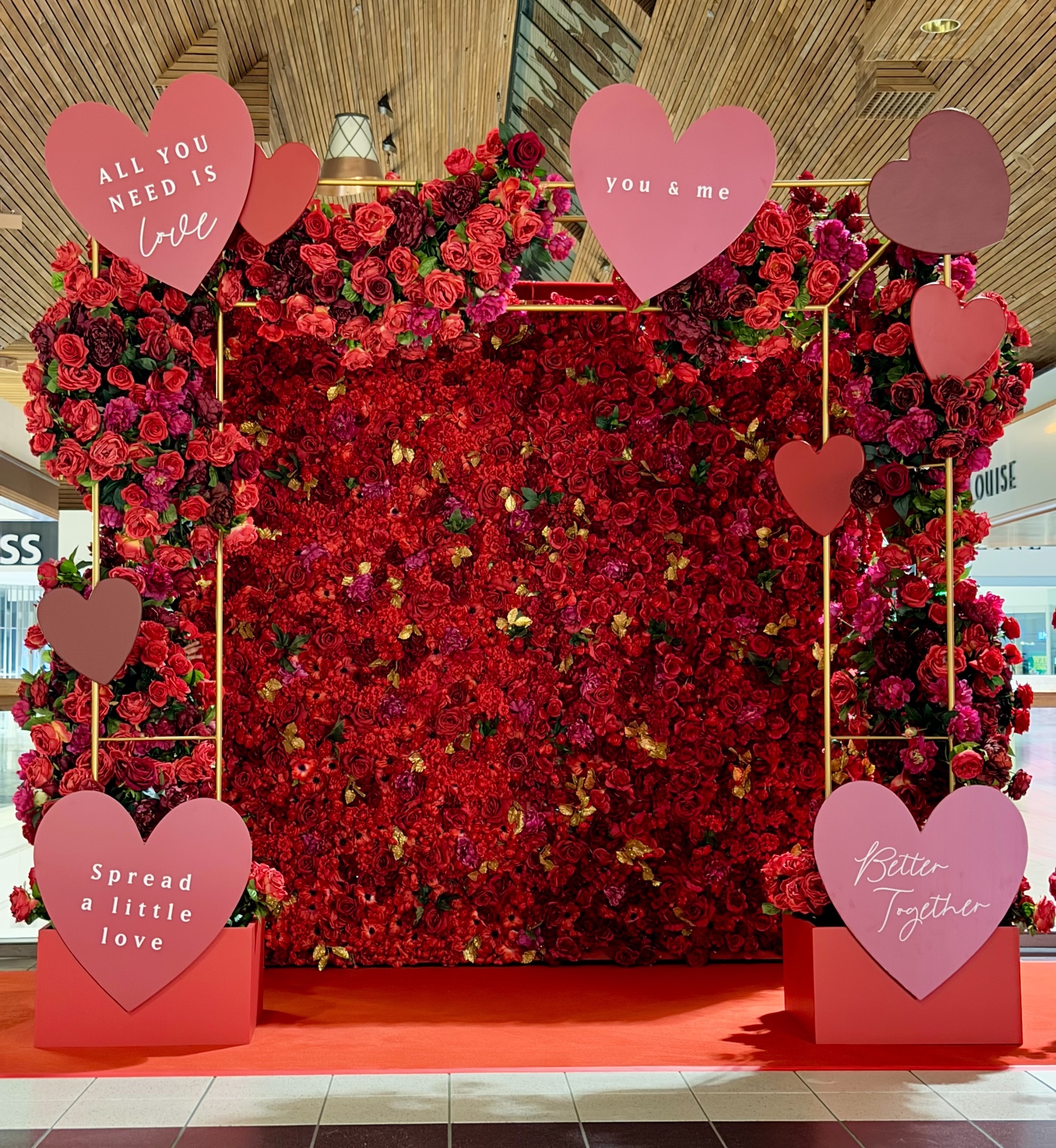 Valentine’s floral wall display with red flowers and heart accents in mall