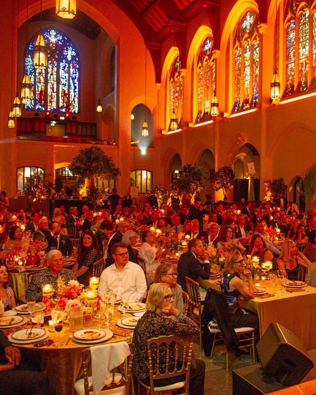 Gala dinner with warm lighting and large artificial tree in banquet hall