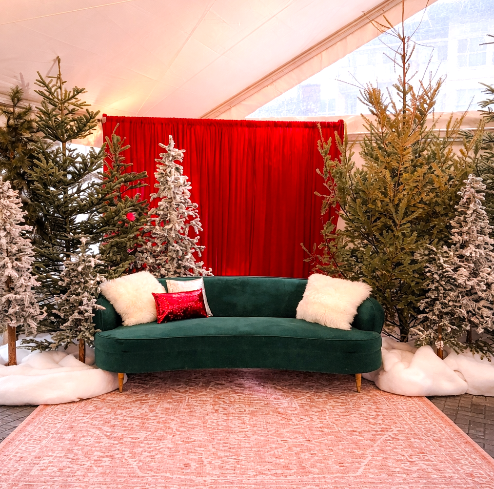 Winter lounge backdrop with evergreen trees and seating area for event