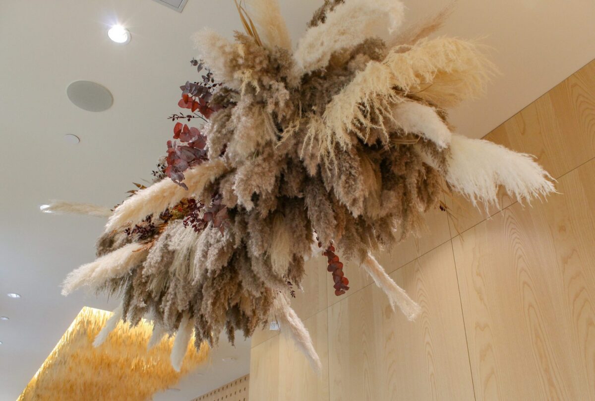 Large ceiling-mounted faux pampas grass and dried floral installation.